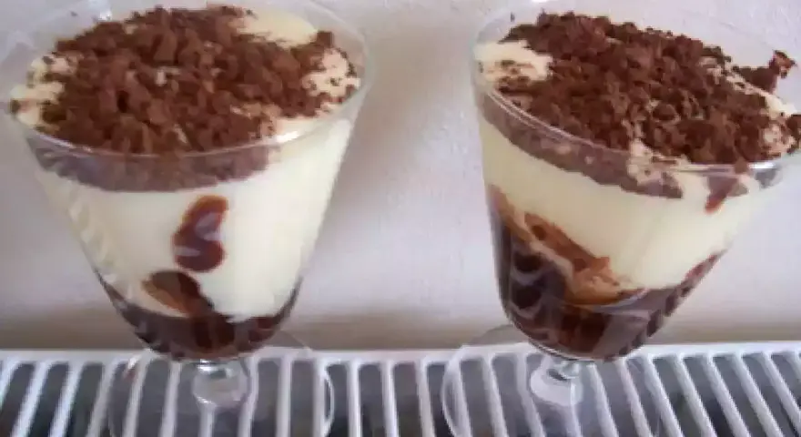 Deux verrines de tiramisu Nutella, crémeux et gourmand, saupoudrées de cacao. Un délice pour les yeux et les papilles.
