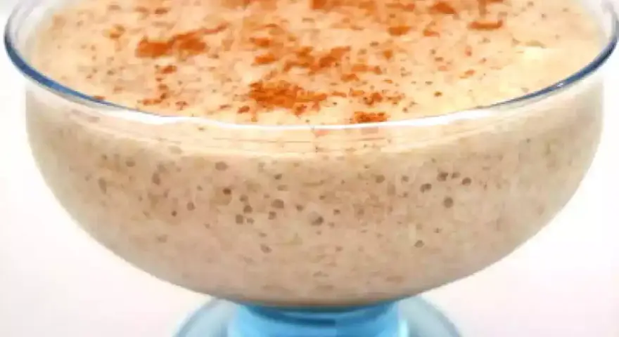 Un déliceux mousse banane crémeuse, saupoudrée de cannelle, servie dans un joli bol en verre bleu.