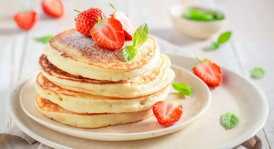 Pile de pancakes moelleux, décorés de fraises fraîches et de menthe, comme ceux de Cyril Lignac. Un délice !
