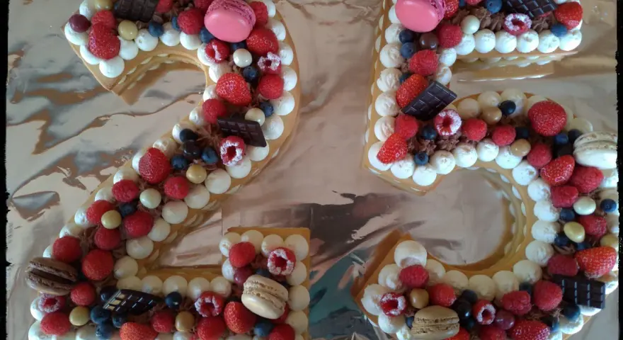 Gâteau chiffre 25 décoré de chantilly mascarpone, framboises, fraises, myrtilles, macarons et chocolat.