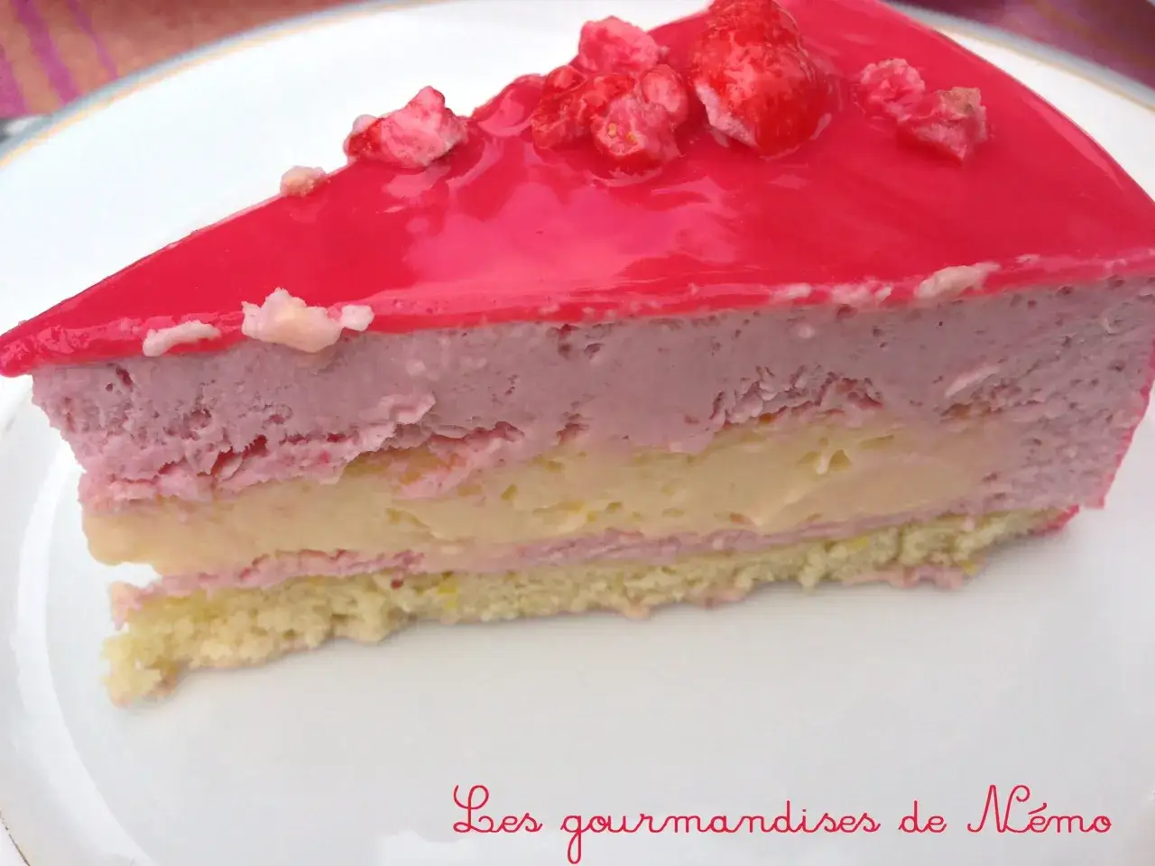 Tranche d'entremet fraise, rose et jaune, sur une assiette blanche. D&eacute;licieux et gourmand !