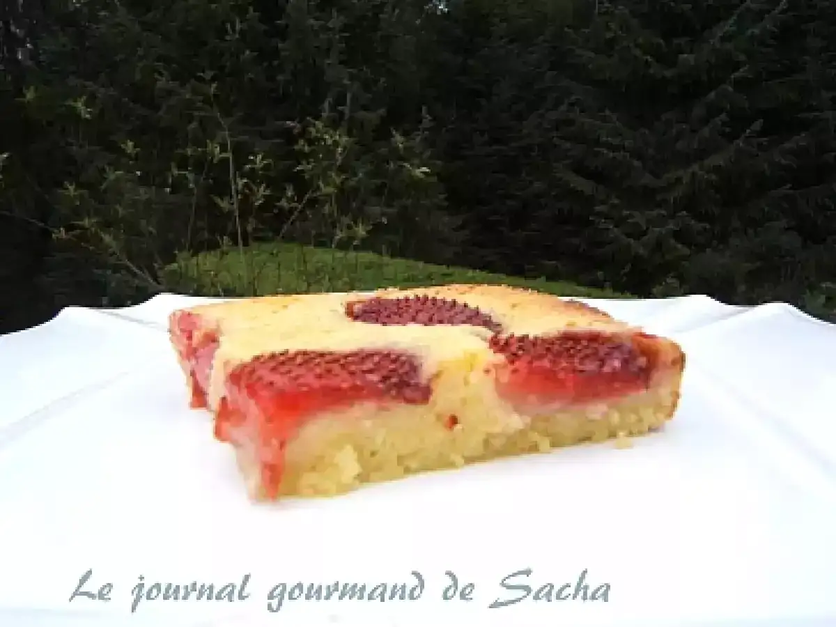 Un morceau de clafoutis aux fraises, moelleux et parfum&eacute;, servi sur une assiette blanche, avec un fond de verdure.