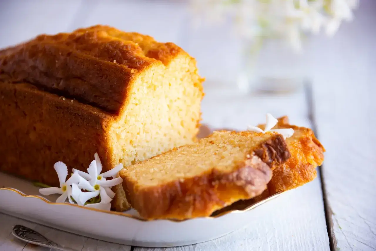 Un d&eacute;licieux quatre-quarts dor&eacute;, tranch&eacute; et d&eacute;cor&eacute; de fleurs blanches sur une assiette &eacute;l&eacute;gante.