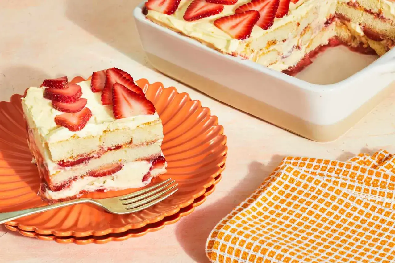 Une part de tiramisu fraise, légère et crémeuse, garnie de fruits rouges frais, sur une assiette orange.