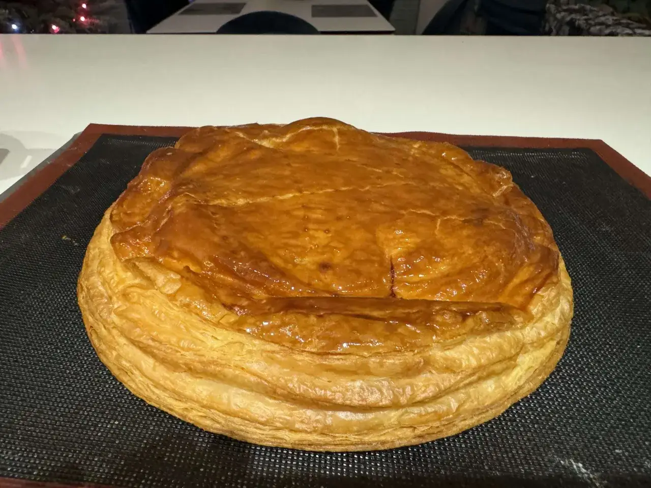 Une galette des rois coco dor&eacute;e et feuillet&eacute;e, pr&ecirc;te &agrave; &ecirc;tre d&eacute;gust&eacute;e. Son dessus est l&eacute;g&egrave;rement craquel&eacute;, promettant une texture d&eacute;licieuse.