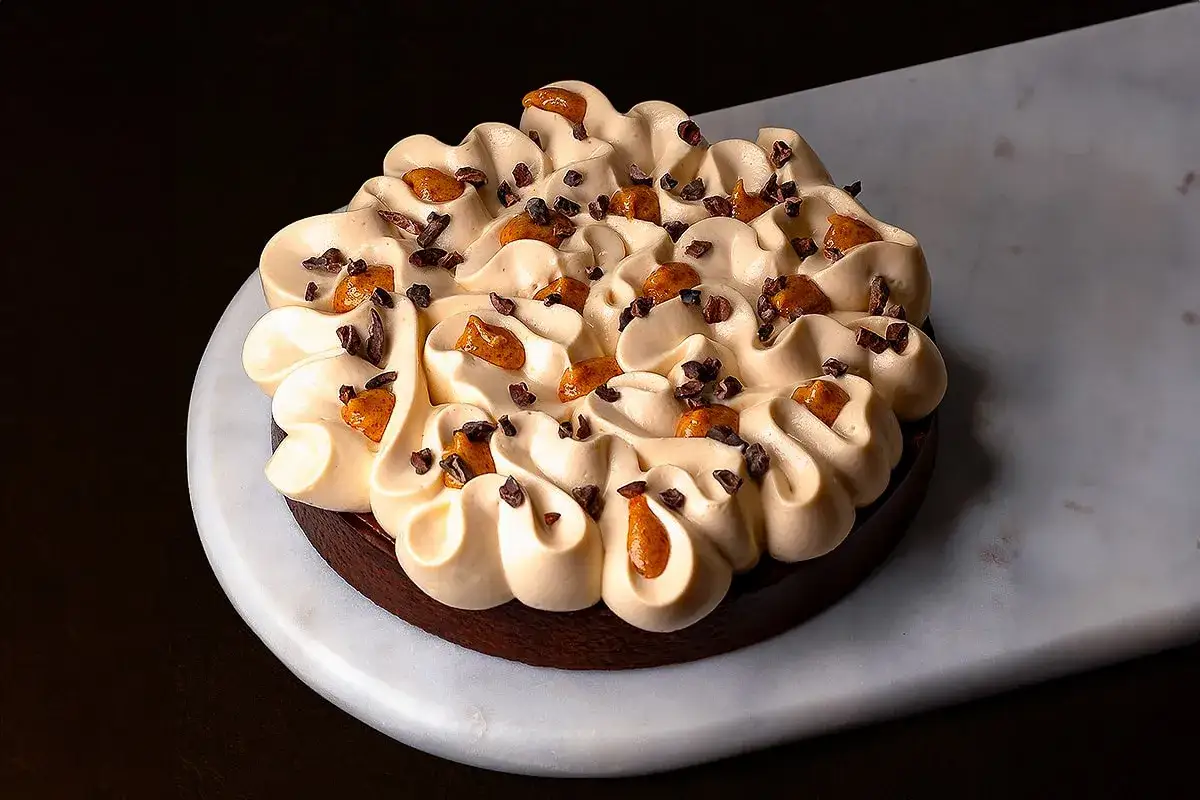 G&acirc;teau fa&ccedil;on snickers, une gourmandise au chocolat et caramel, garni de cr&egrave;me onctueuse et de &eacute;clats de cacao.