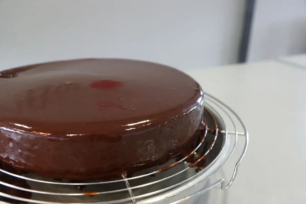 G&acirc;teau rond avec un gla&ccedil;age chocolat brillant, encore d&eacute;goulinant sur une grille.