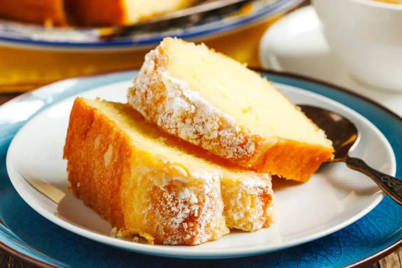 Deux parts de g&acirc;teau au yaourt, saupoudr&eacute;es de sucre glace, sur une assiette blanche et bleue.