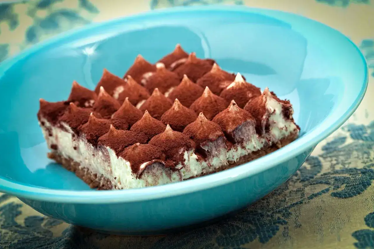 Un d&eacute;licieux tiramisu, pr&ecirc;t &agrave; &ecirc;tre d&eacute;gust&eacute;, dans un plat bleu vif. Une invitation &agrave; suivre la recette !