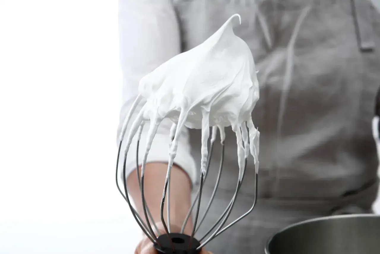 Meringue italienne on a whisk, a cloud of sweetness ready for a dessert.