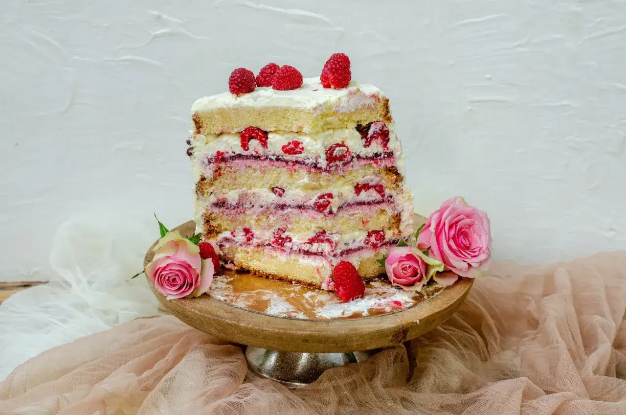 Un g&acirc;teau d'anniversaire facile et bluffant, aux multiples couches de g&eacute;noise, cr&egrave;me et framboises, d&eacute;cor&eacute; de roses roses.