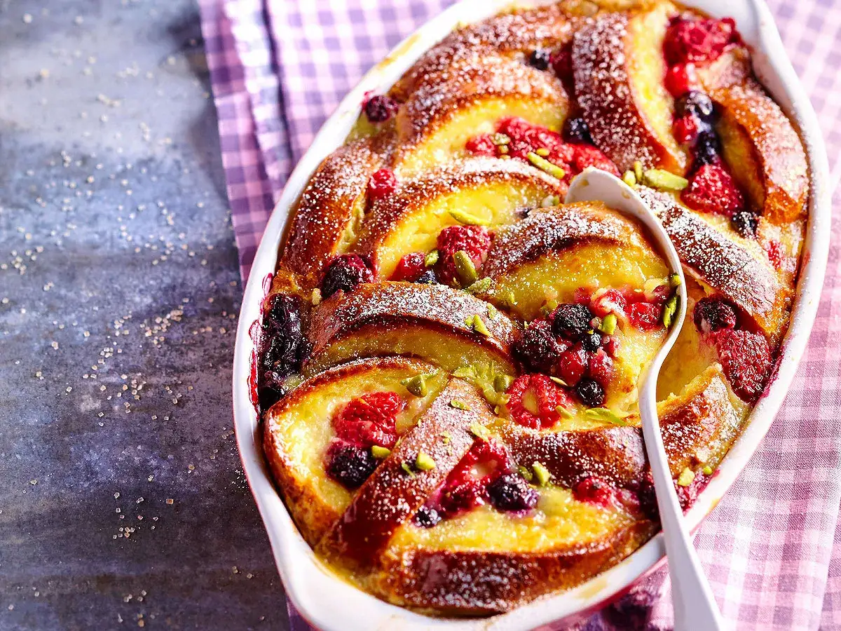 Un d&eacute;licieux pain perdu aux fruits rouges et pistaches, saupoudr&eacute; de sucre glace, servi dans un plat blanc.