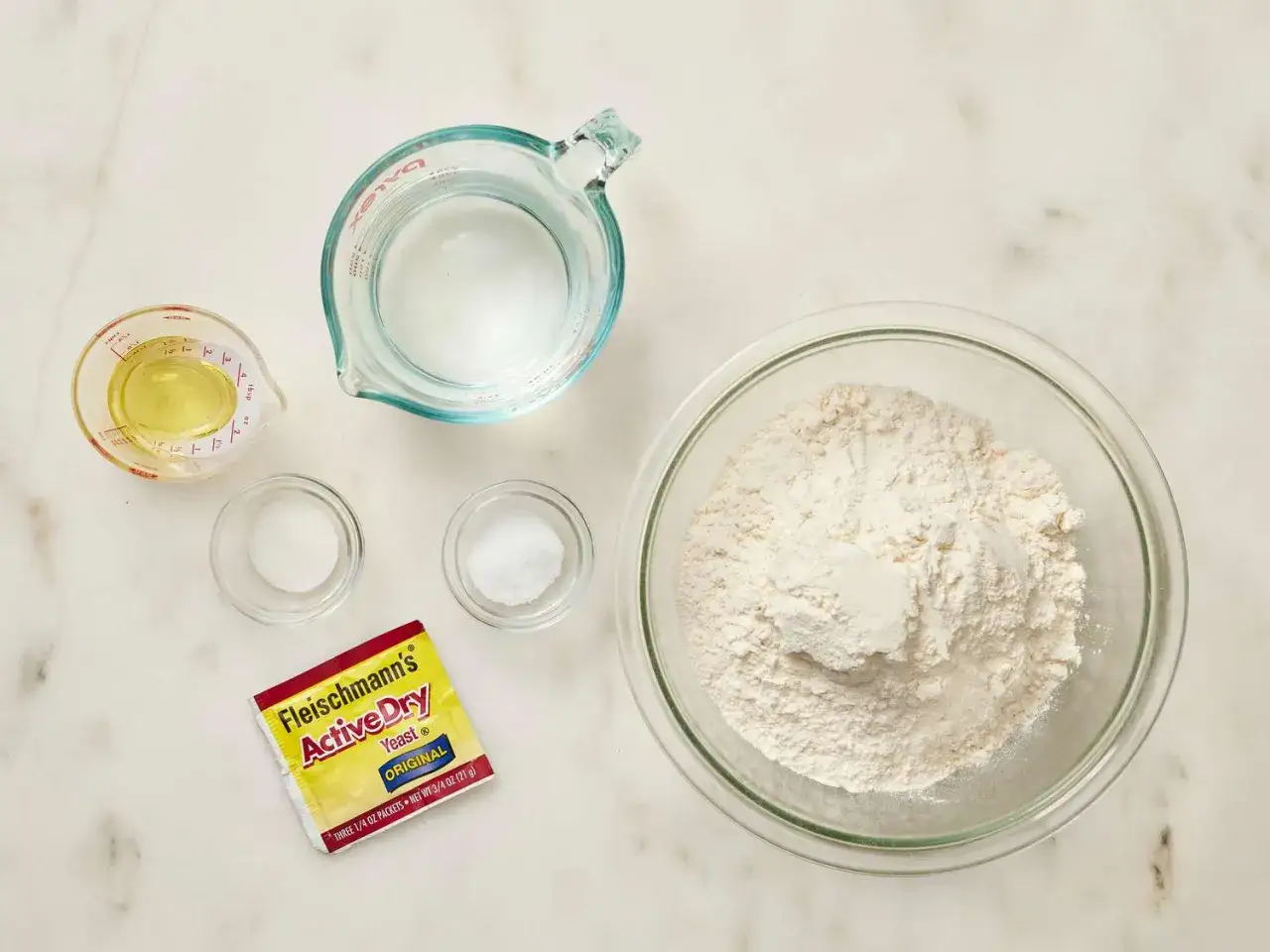 Ingr&eacute;dients pour une recette p&acirc;te &agrave; pizza rapide : farine, eau, levure, sel et huile.