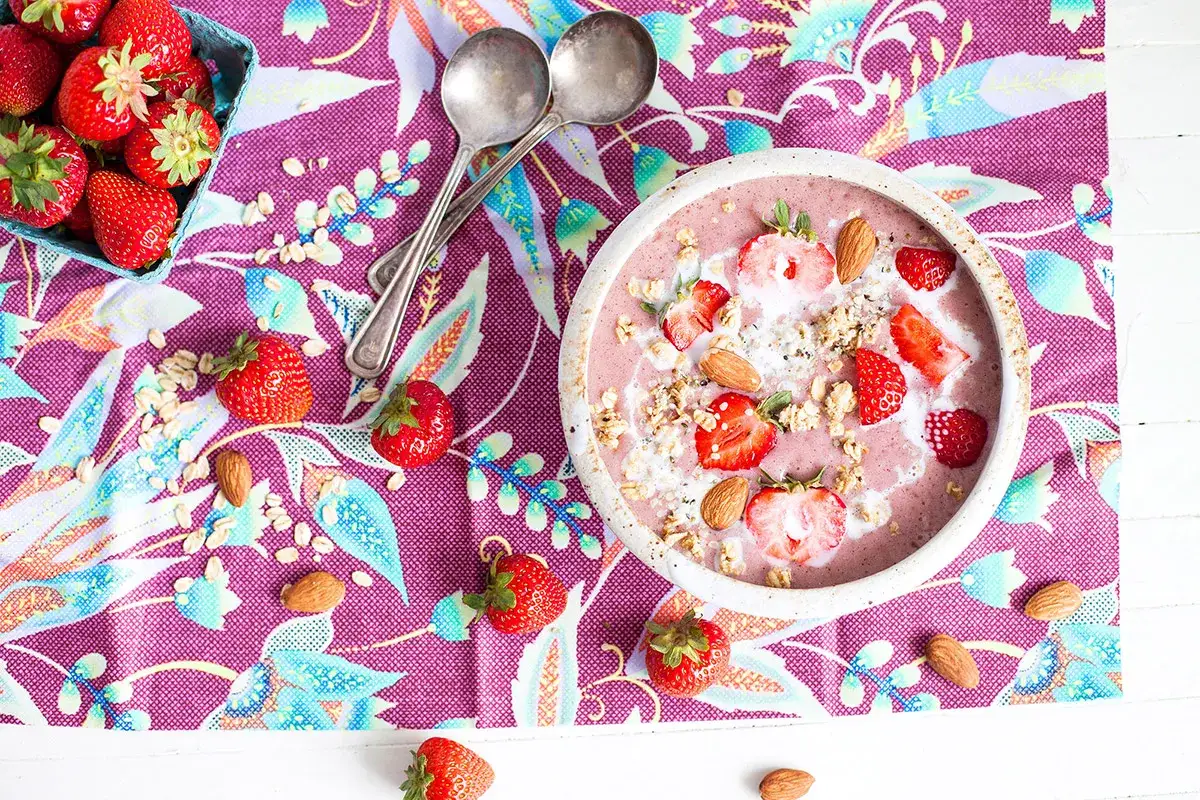 Un d&eacute;licieux smoothie fraise garni de fruits frais, d'amandes et de granola, pr&ecirc;t &agrave; &ecirc;tre d&eacute;gust&eacute;.