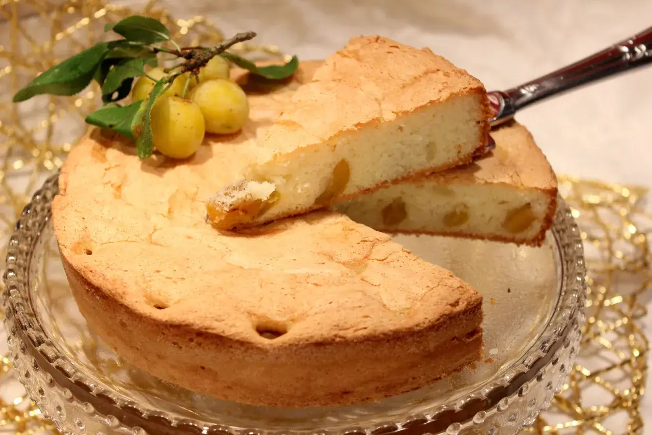 G&acirc;teau lorrain aux mirabelles, une part coup&eacute;e r&eacute;v&egrave;le les fruits dor&eacute;s. Une branche de mirabelles d&eacute;core ce d&eacute;lice.
