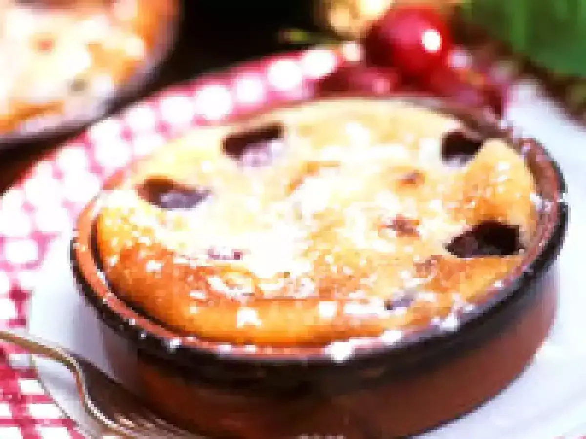 Un d&eacute;licieux clafoutis aux prunes, saupoudr&eacute; de sucre glace, dans un ramequin en terre cuite.