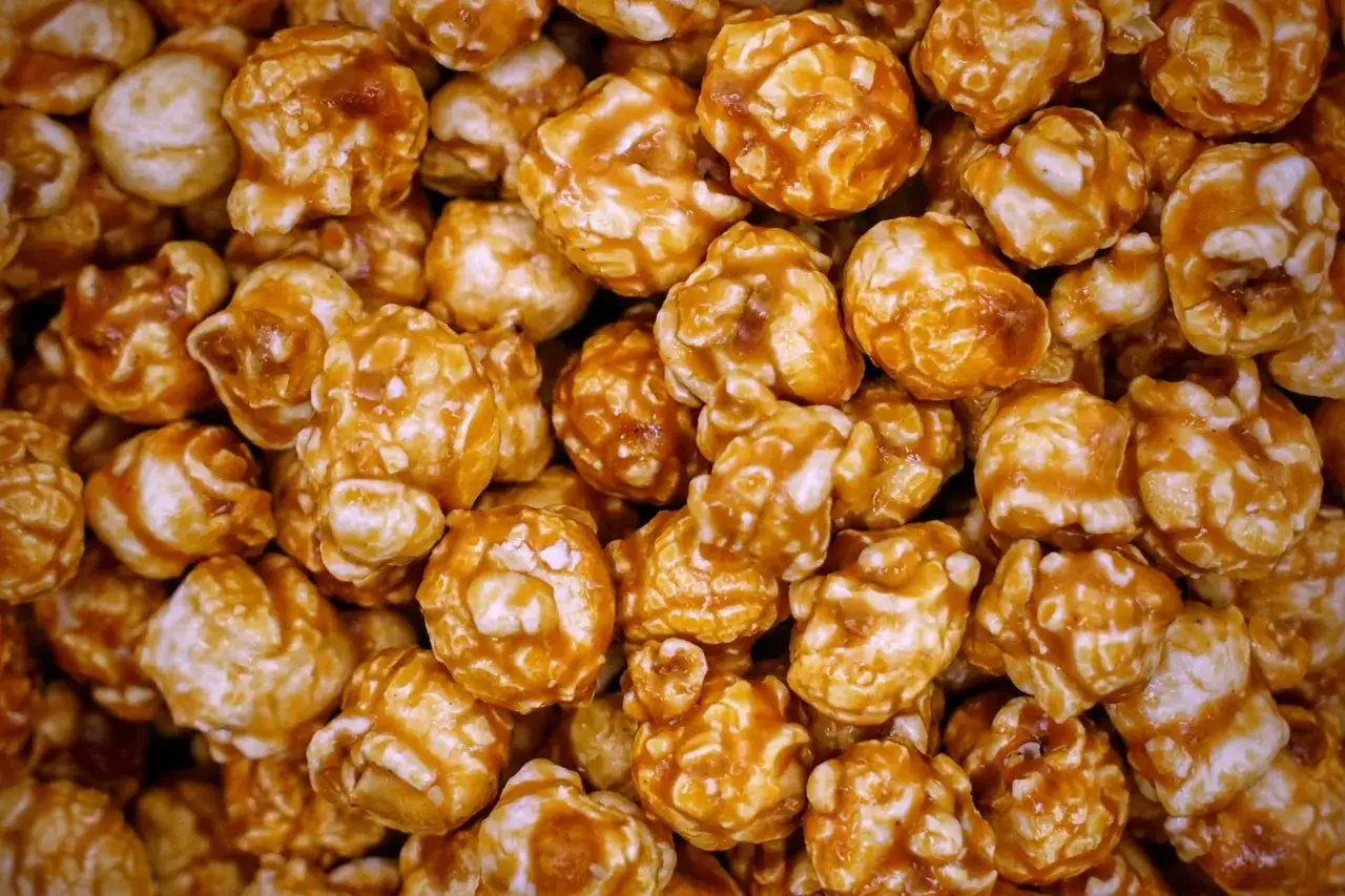 Un gros plan sur du pop-corn au caramel, chaque grain est enrobé d'une sauce dorée et collante.