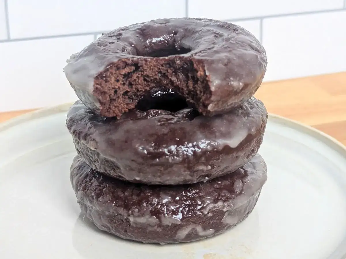 Pile de 3 donuts au chocolat glac&eacute;, un d&eacute;lice pour toute recette donuts.