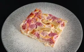 Tranche de clafoutis rhubarbe aux fruits rouges, sur une assiette transparente aux motifs rayonnants.
