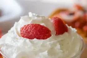 Chantilly aérienne garnie de fraises fraîches. Une invitation à découvrir comment faire de la chantilly maison pour un dessert parfait.