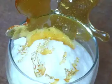 Un verre de crème aérienne surmonté d'une décoration en caramel craquant. Ces oeufs à la neige sont prêts à être dégustés.
