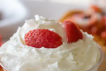 Chantilly aérienne garnie de fraises fraîches. Une invitation à découvrir comment faire de la chantilly maison pour un dessert parfait.