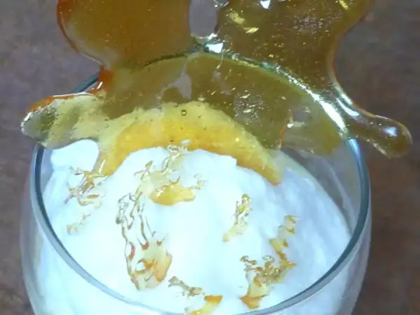Un verre de crème aérienne surmonté d'une décoration en caramel craquant. Ces oeufs à la neige sont prêts à être dégustés.