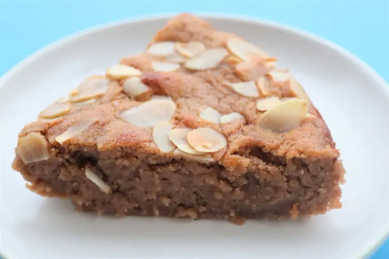 Tranche de gâteau à la crème de marron, garnie d'amandes effilées, sur une assiette blanche.