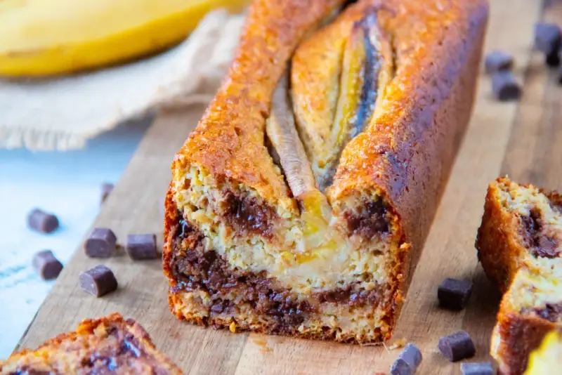 Un délicieux banana bread aux pépites de chocolat, garni de bananes sur le dessus, prêt à être dégusté.